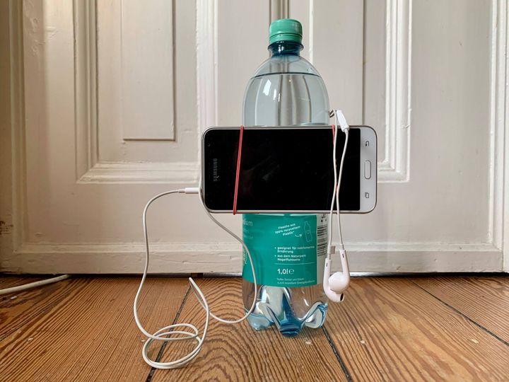Das Bild zeigt, wie ein Smartphone mit einem Gummiring an der Wasserflasche befestigt ist. Solch ein einfaches Stativ ist für viele Situationen völlig ausreichend.