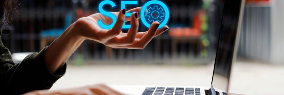 Artikelbild zum Thema Suchmaschinenoptimierung mit Wordpress. Es zeigt eine Hand mit dem Schriftzug SEO vor einem Laptop.